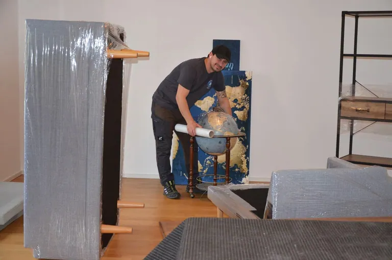 Mitarbeiter trägt verpackte Möbel in einer Wohnung